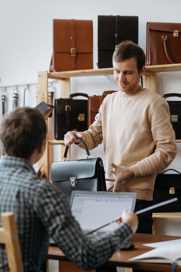 Two men discussing and buying leather bags in an elegant shop environment.