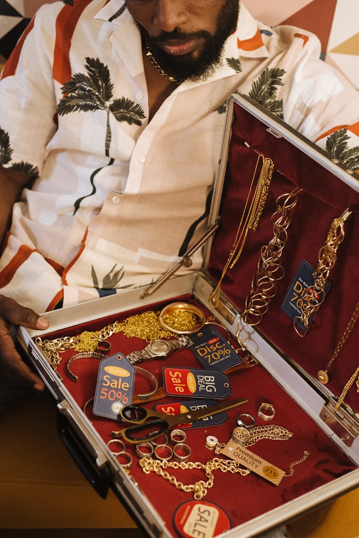 trusted-partner A man showcasing a diverse collection of gold jewelry and sale tags in a briefcase.